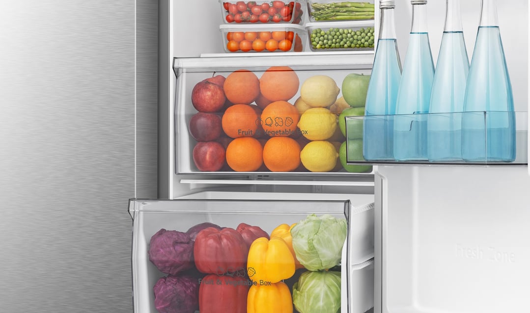 Open fridge interior showing fruit, vegetables, and bottled water on shelves