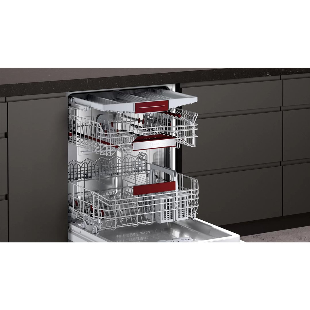 Open built-under dishwasher with racks pulled out in a dark kitchen