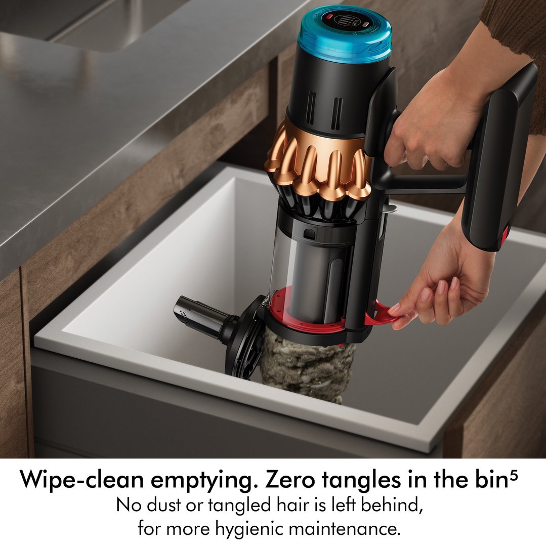 Hand emptying a Dyson handstick vacuum into a kitchen sink