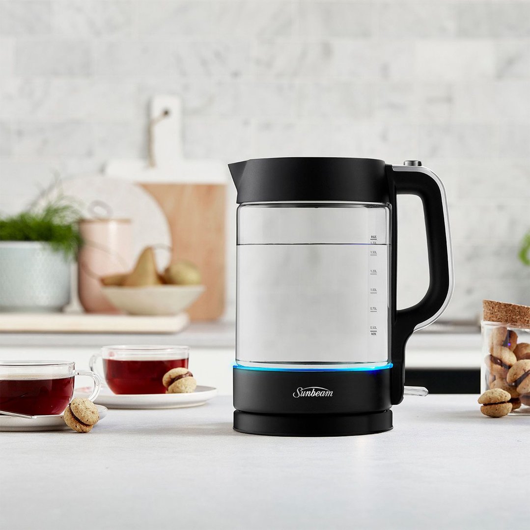 Sunbeam 1.7L Black Classics Glass Kettle on a kitchen counter with tea and biscuits