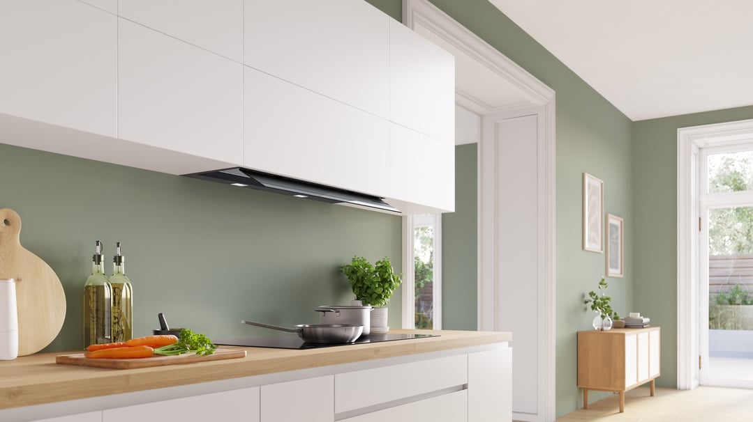 Integrated rangehood in a modern kitchen with white cabinets and green walls