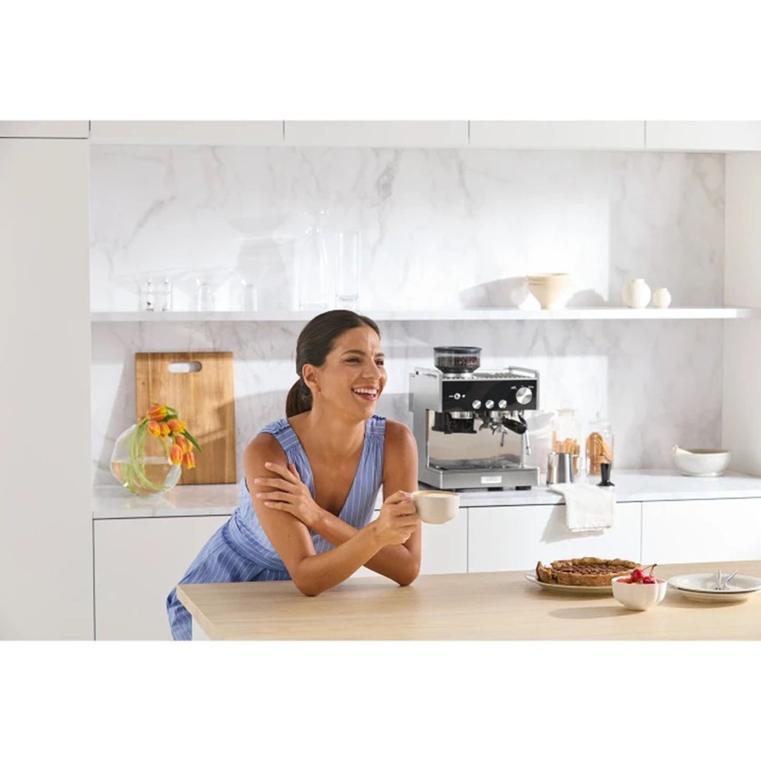 Woman holding a cup of coffee next to the espresso coffee machine