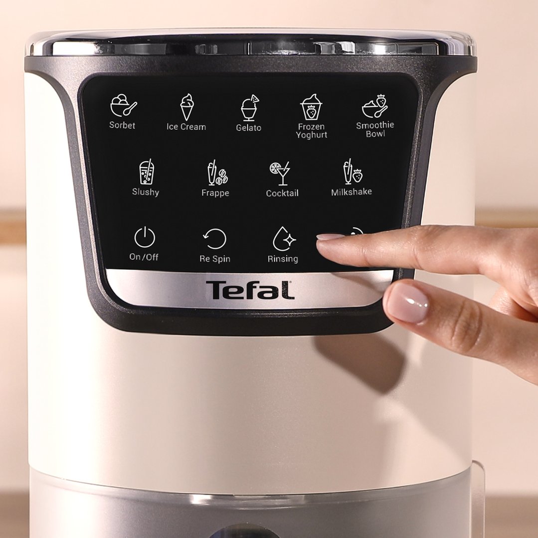 Hand pressing the rinsing button on the control panel of an ice cream maker