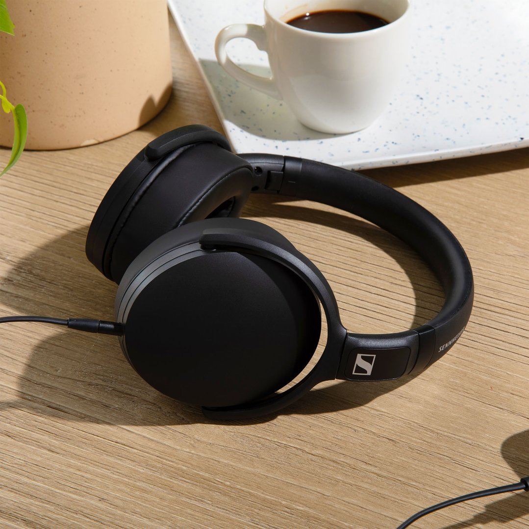 Black Sennheiser HD 400U USB-C wired headphones on a wooden table with coffee