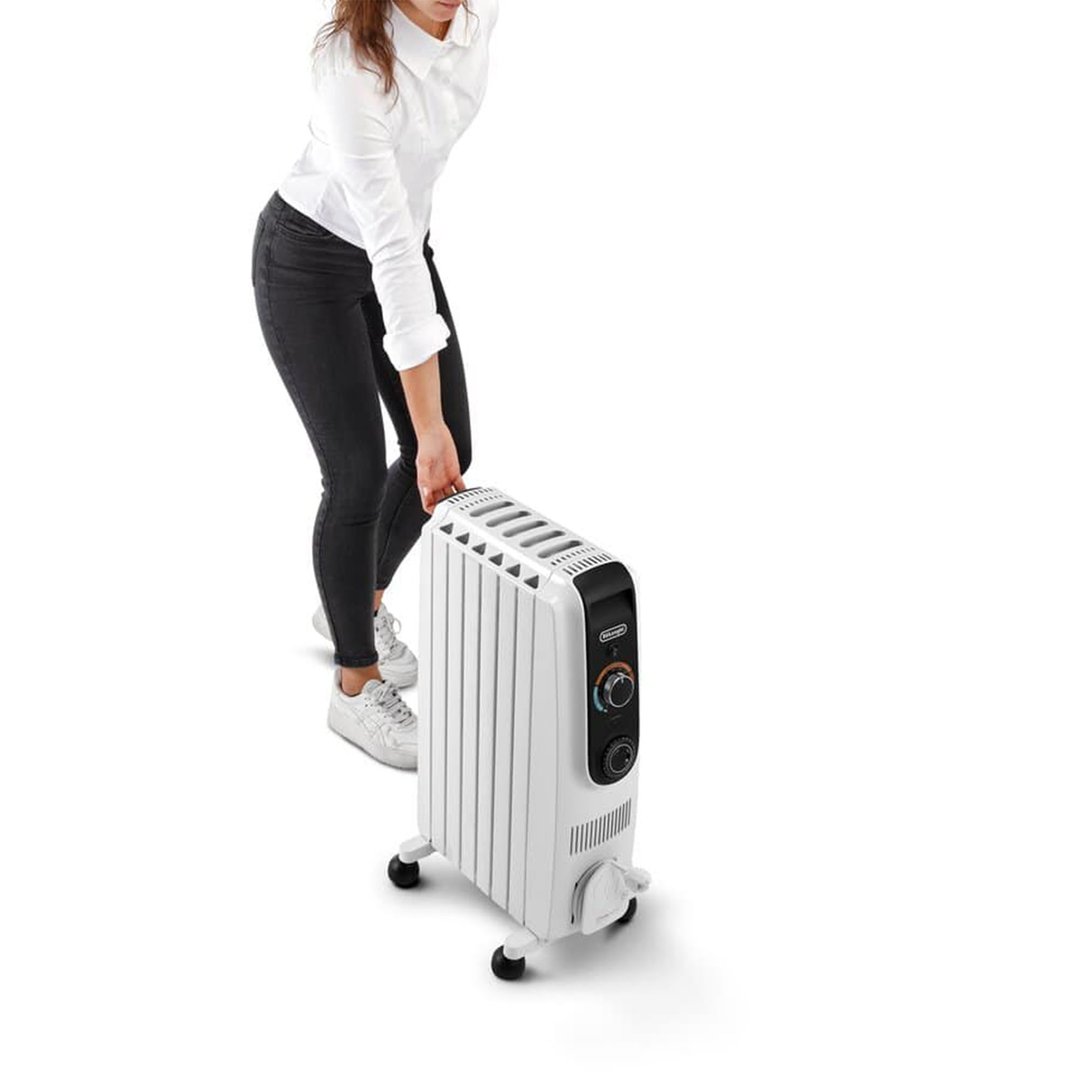 Woman in black jeans and white shirt moving a white oil column heater
