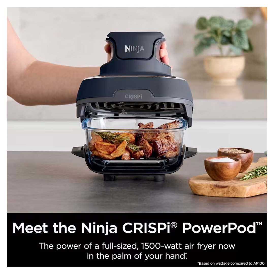 Hand holding the Ninja CRISPI PowerPod air fryer with food inside on a kitchen counter