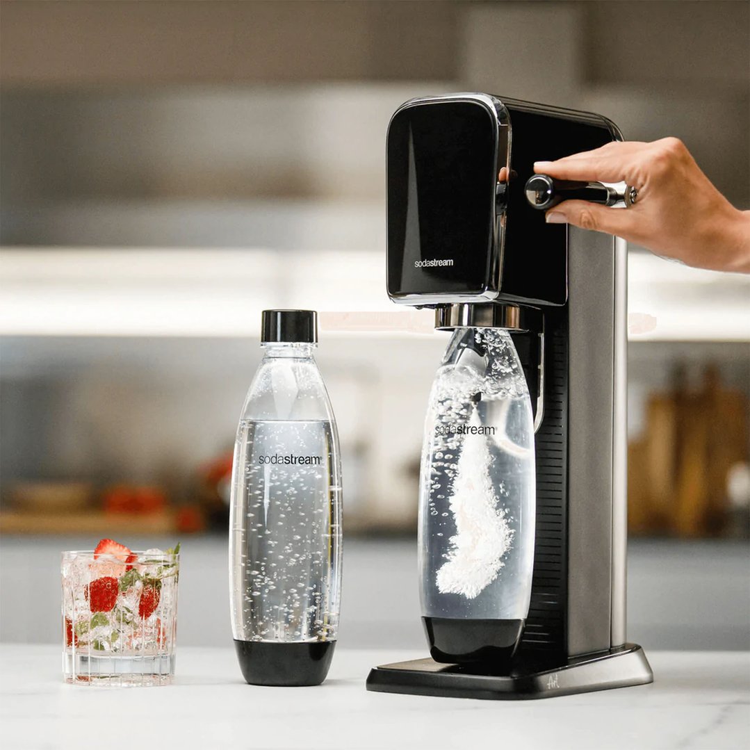 Hand operating a black SodaStream Art sparkling water maker on a kitchen counter