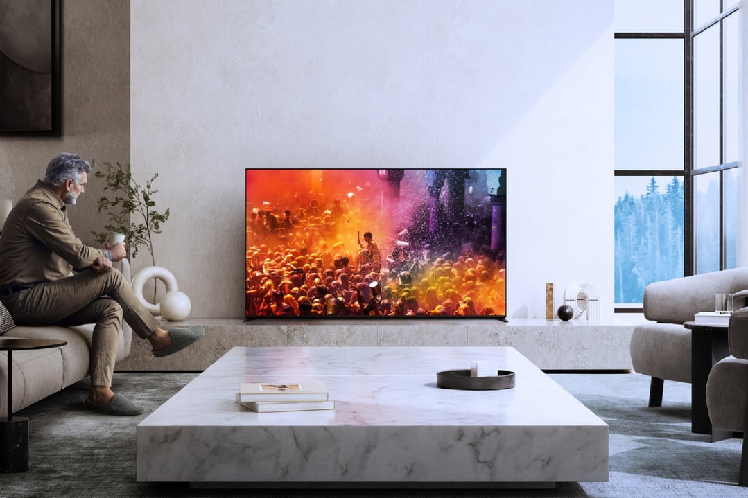 Man watching a TV displaying a colorful festival scene in a modern living room