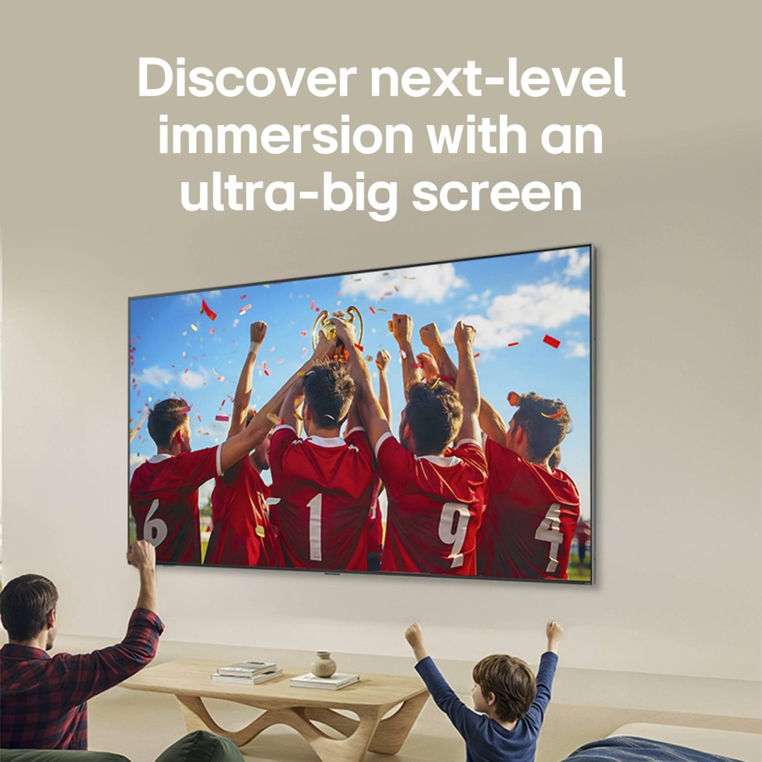 Father and son watching a soccer game on a large TV in a living room