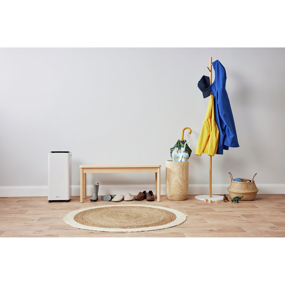 White Breville dehumidifier in an entryway with a bench, coat rack, and rug