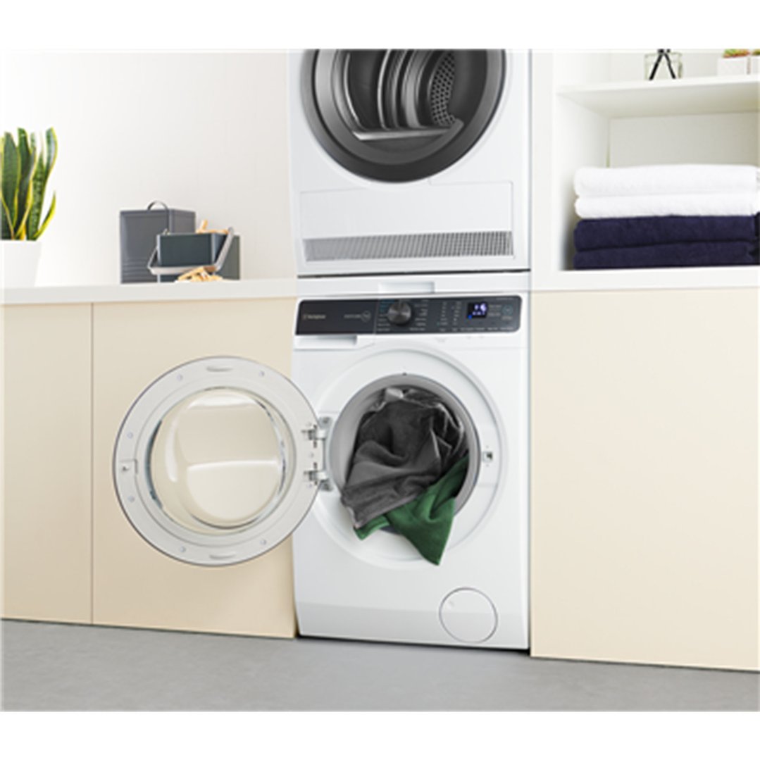 White washing machine with open door and clothes inside, stacked with a dryer