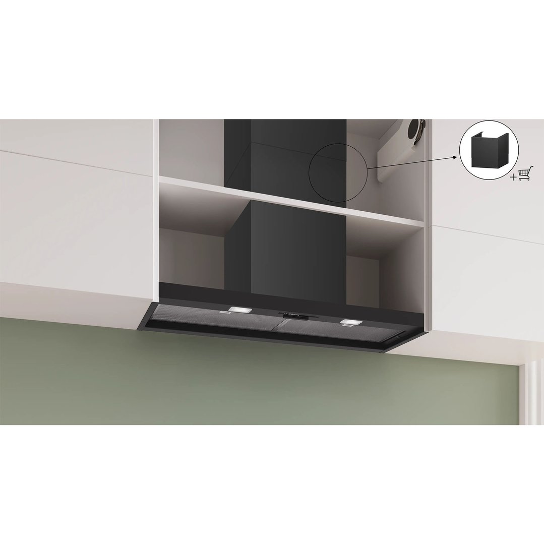 Black integrated rangehood installed in a white kitchen cabinet with a green wall