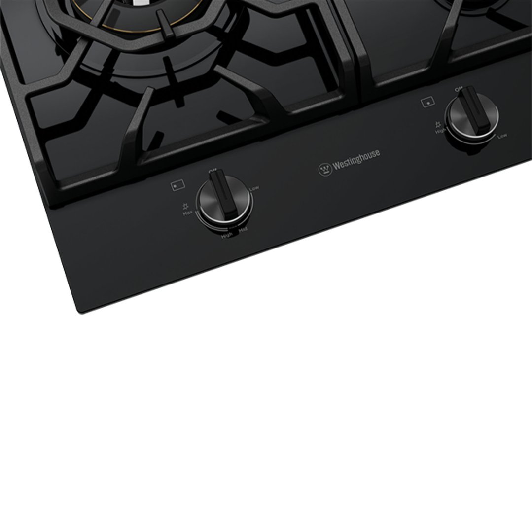 Close-up of a black gas cooktop with control knobs and grates