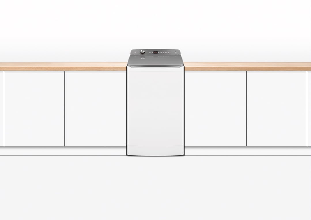 White top loader washing machine in a kitchen setting with wooden countertop