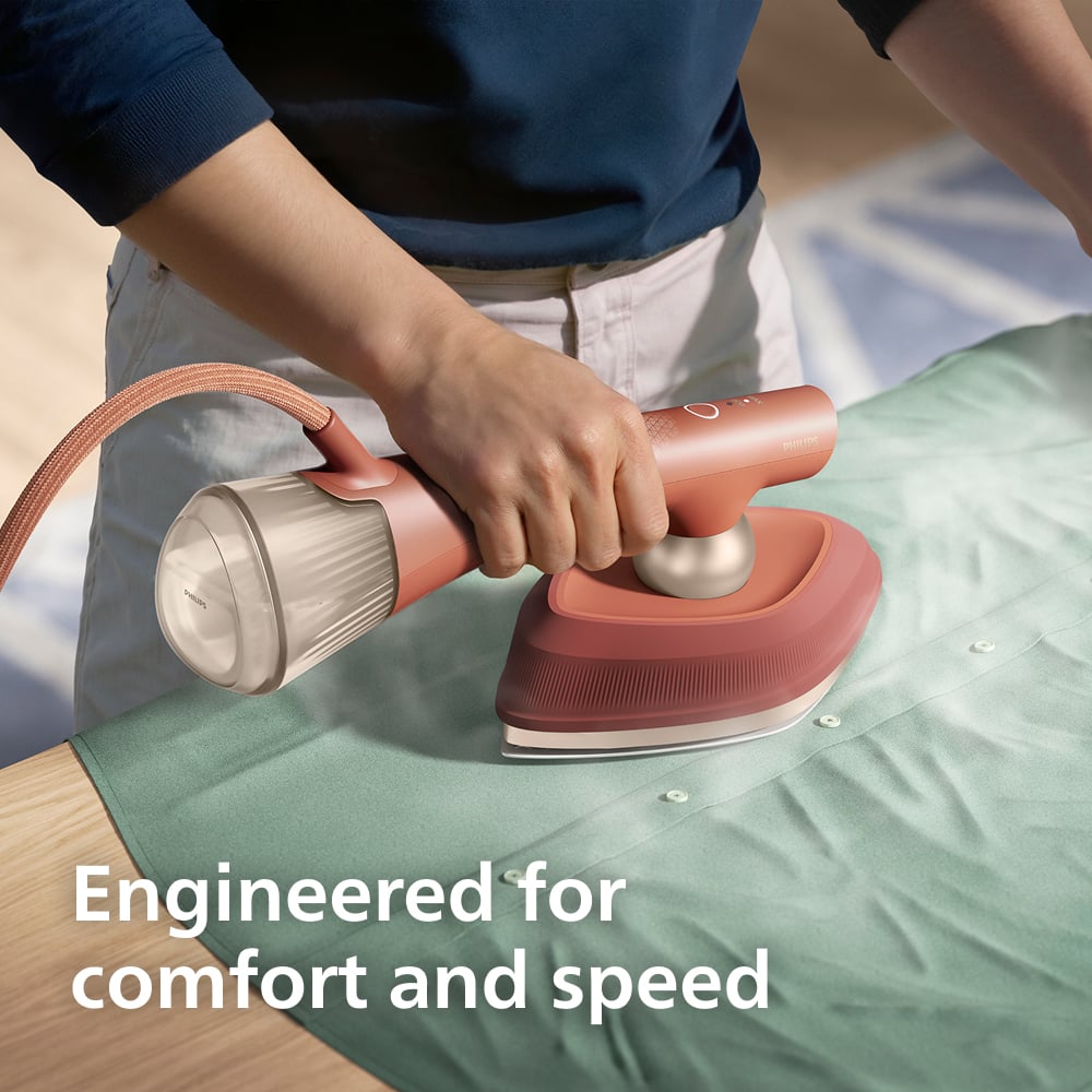 Person holding a Philips OneTurn Hybrid Iron & Steamer on a green shirt