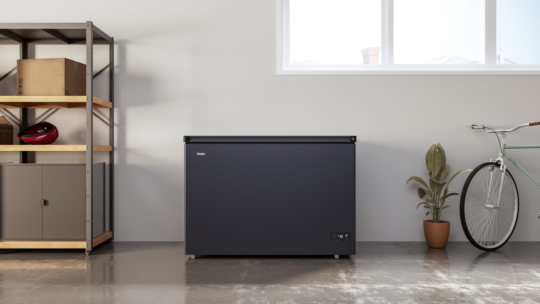 Haier chest freezer in a garage with shelving, a plant, and a bicycle