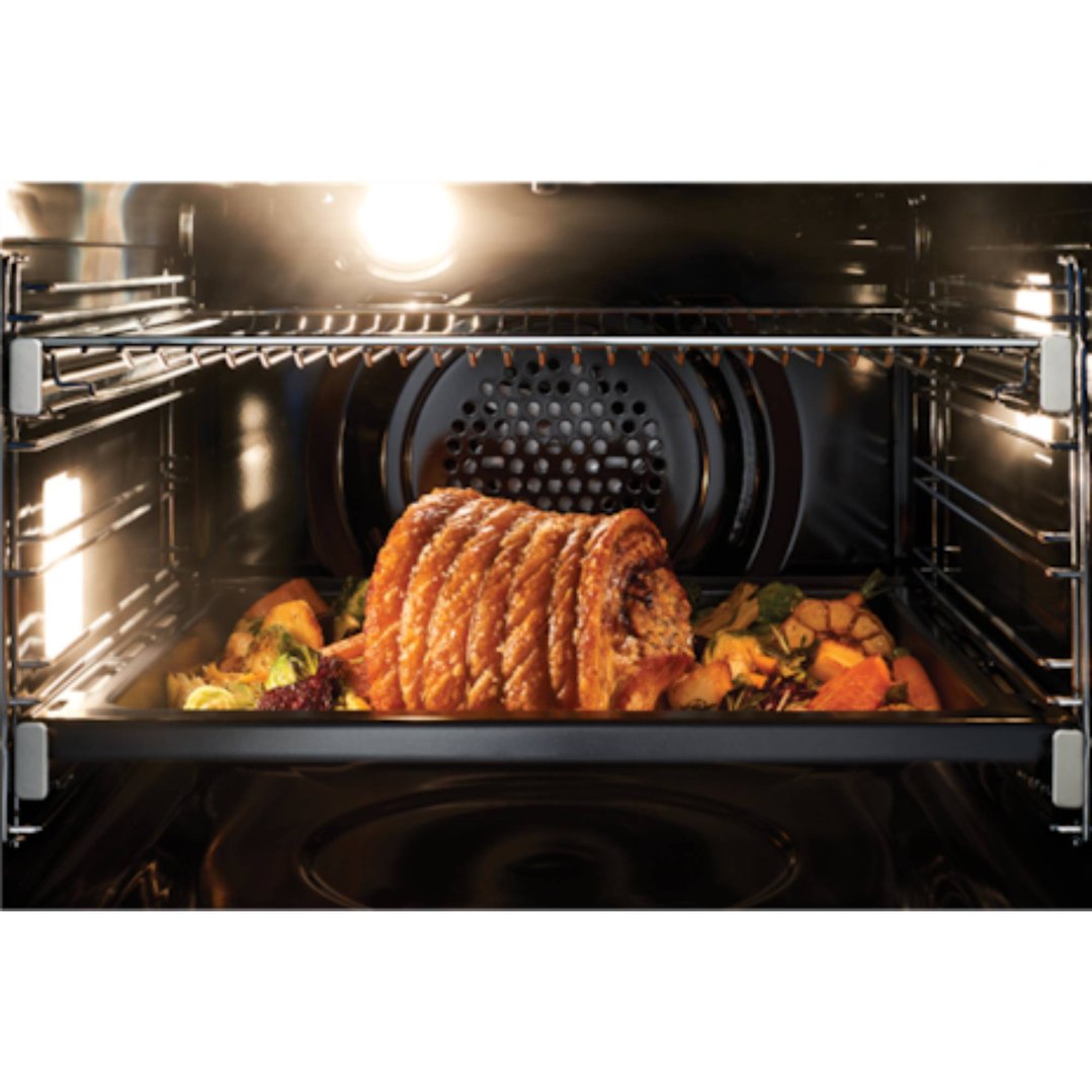 Pork roast and vegetables cooking inside an illuminated oven