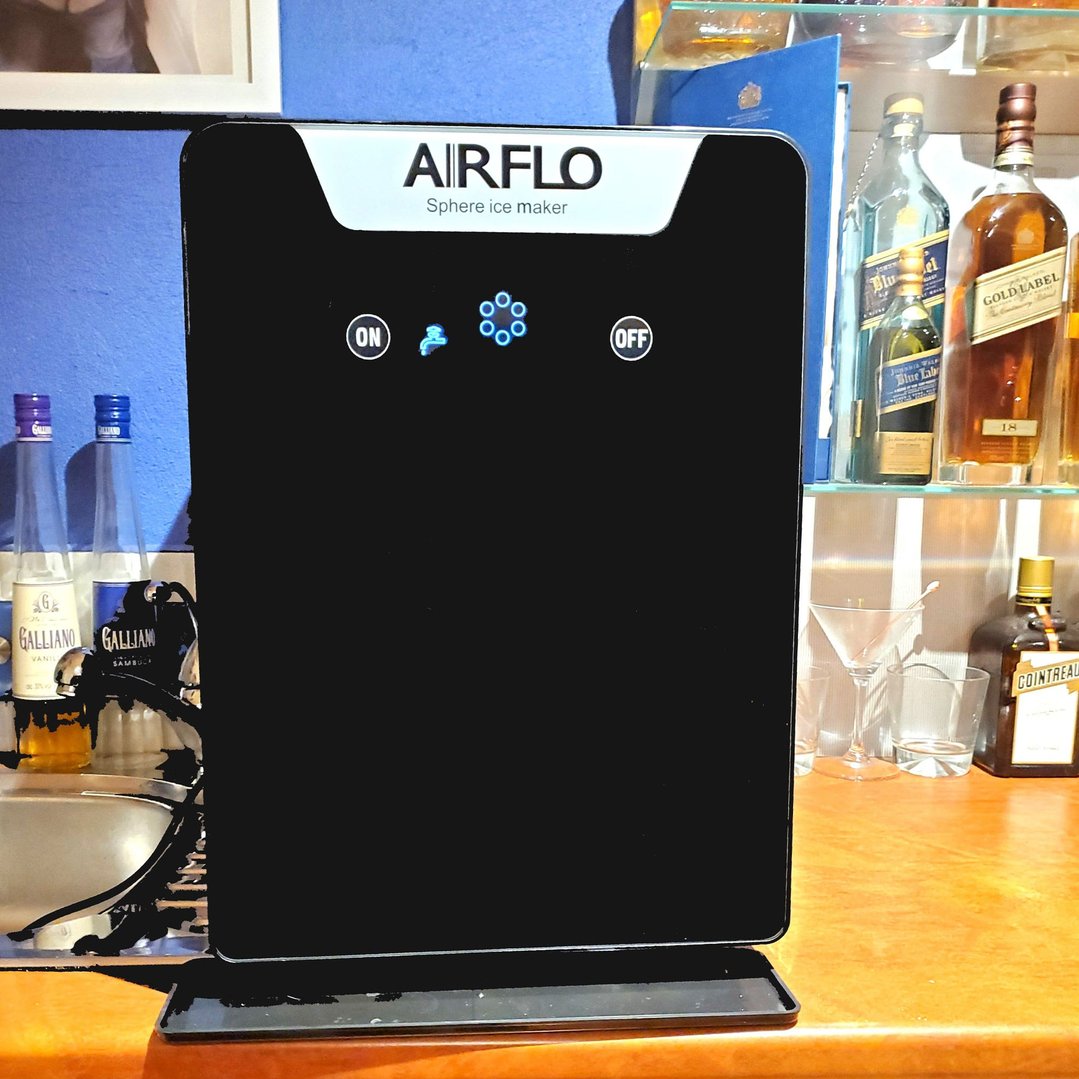 AIRFLO Sphere ice maker on a bar counter with liquor bottles