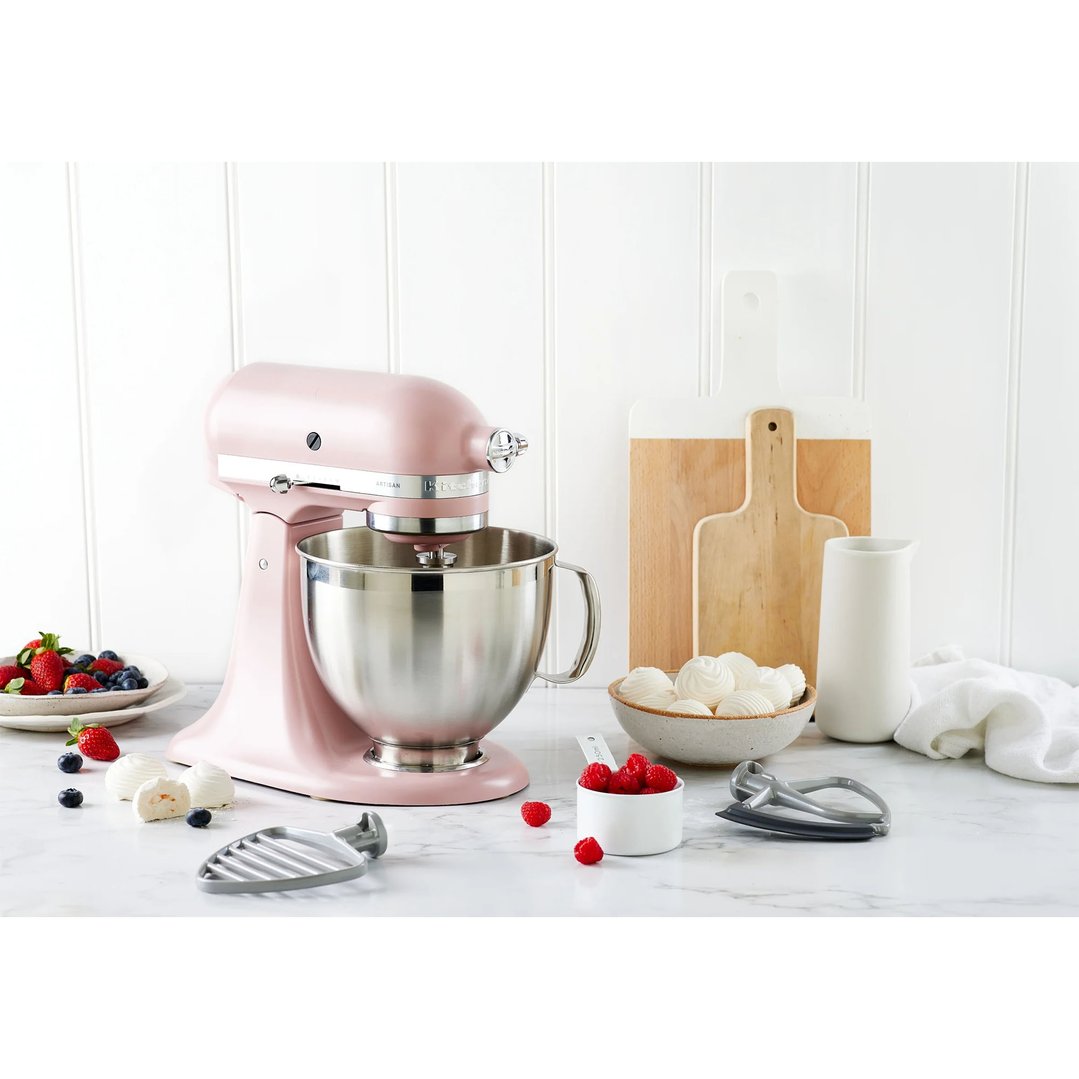 Pink KitchenAid stand mixer on a marble counter with fruit and baking accessories