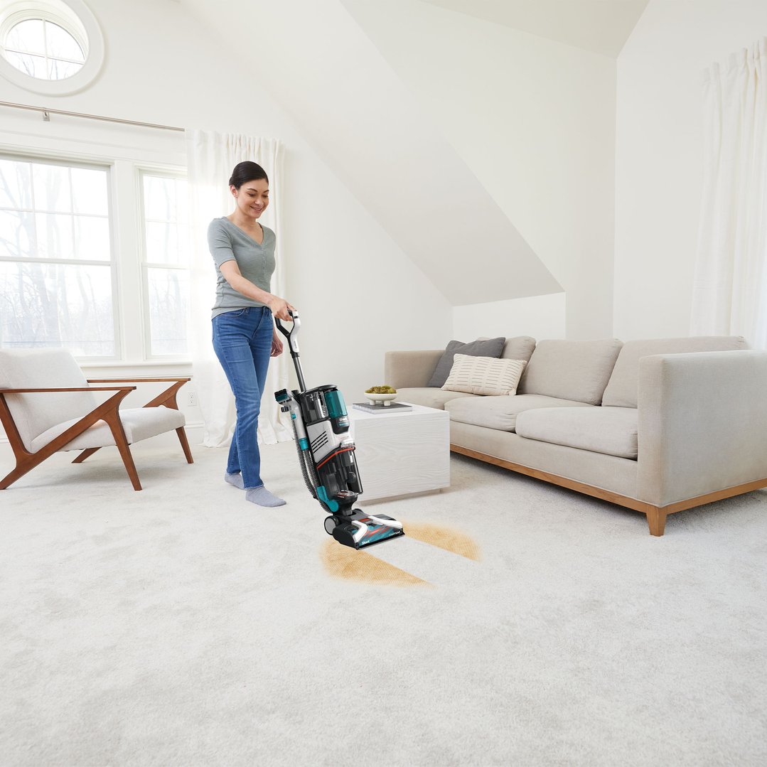 Woman cleaning a stain on a white carpet with a Shark CarpetXpert deep carpet cleaner