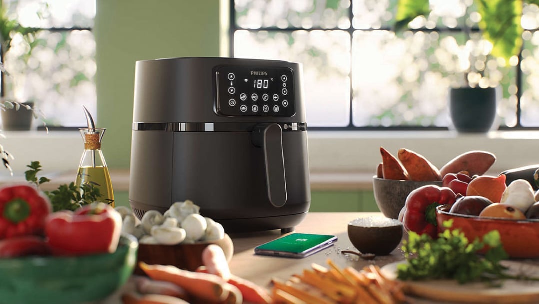 Philips airfryer on a kitchen counter with vegetables and cooking oil