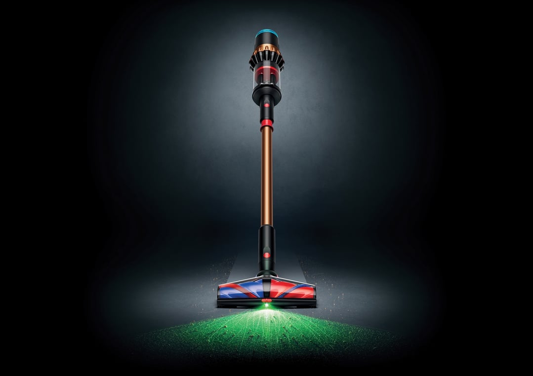 Dyson handstick vacuum with illuminated cleaning head on a dark surface