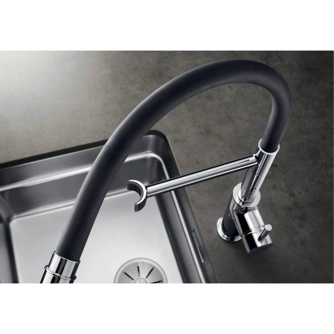 Chrome mixer tap with black flexible hose over a stainless steel sink