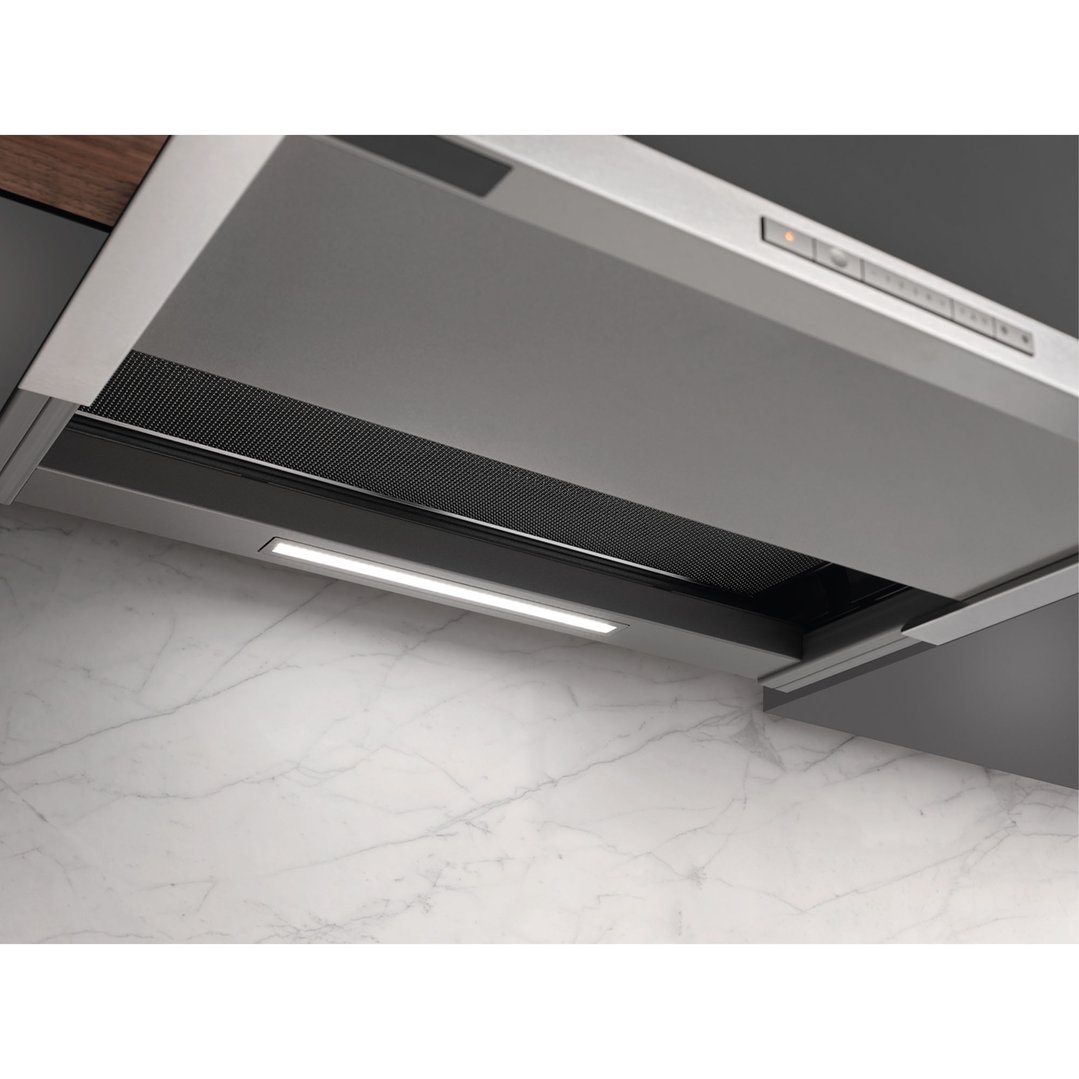 Close up of a rangehood with lights on above a marble benchtop