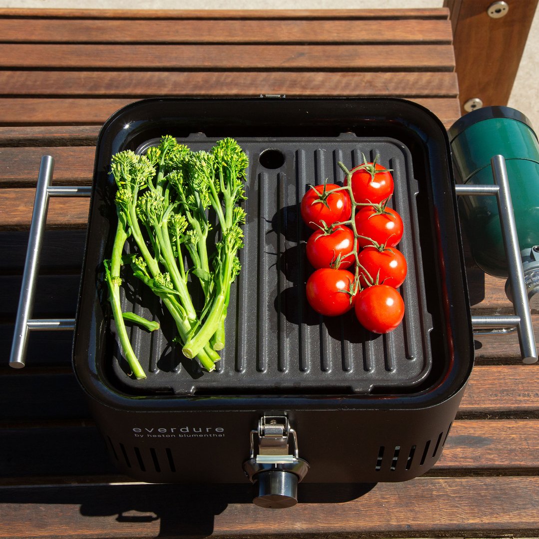 Everdure BBQ with broccoli and tomatoes on a wooden slatted surface outdoors