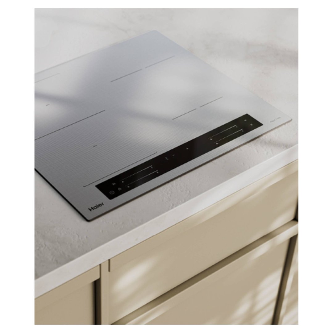 Grey glass induction cooktop with controls, built into a light-colored kitchen bench