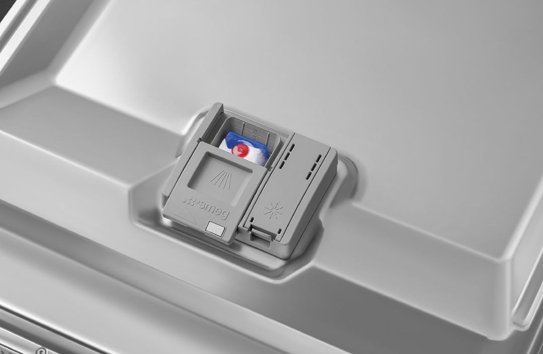 Close-up of a dishwasher's detergent dispenser with a detergent pod inside