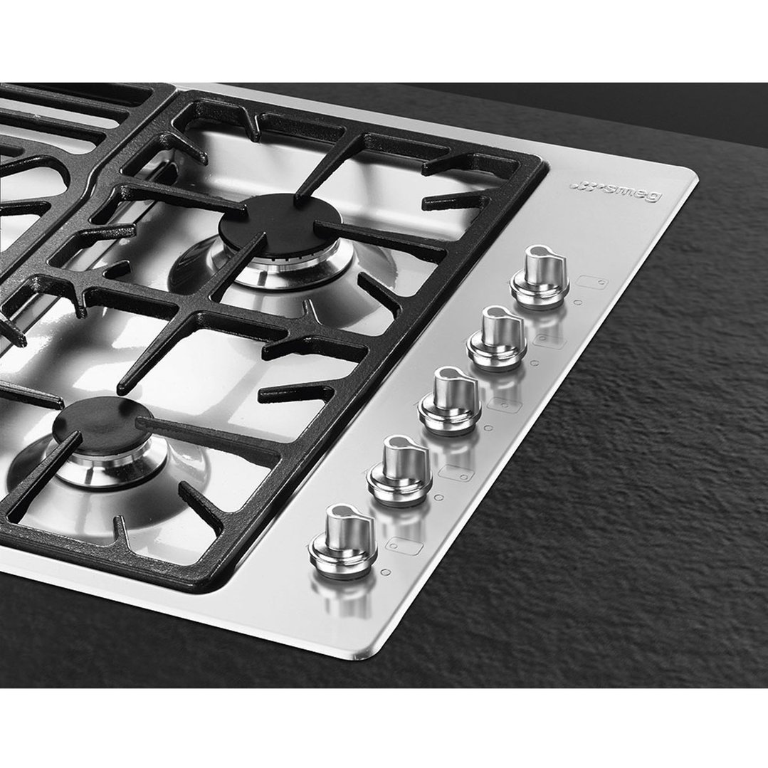 Close up of a stainless steel gas cooktop with five burners and control knobs