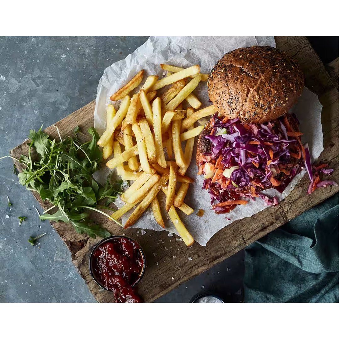 Burger with fries and salad on a wooden board with sauce