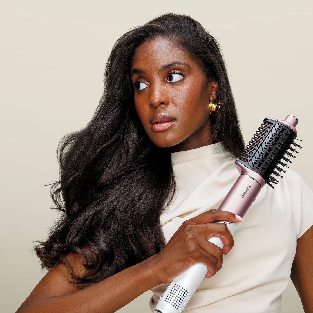 Woman holding a Shark hair styler, looking to the side