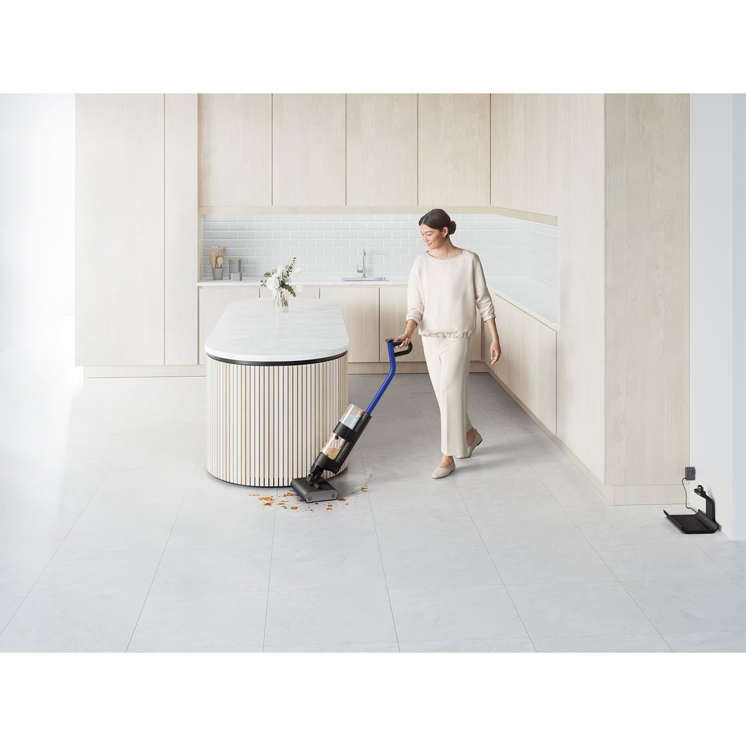 Woman cleaning kitchen floor with a wet cleaner, food debris on floor