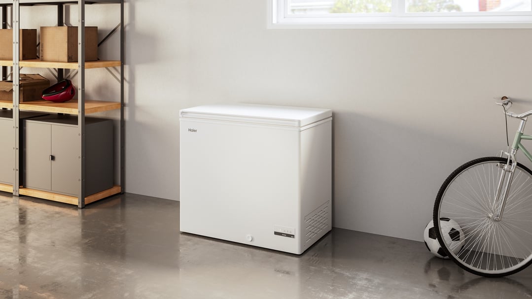 White Haier chest freezer in a garage with shelving and a bicycle