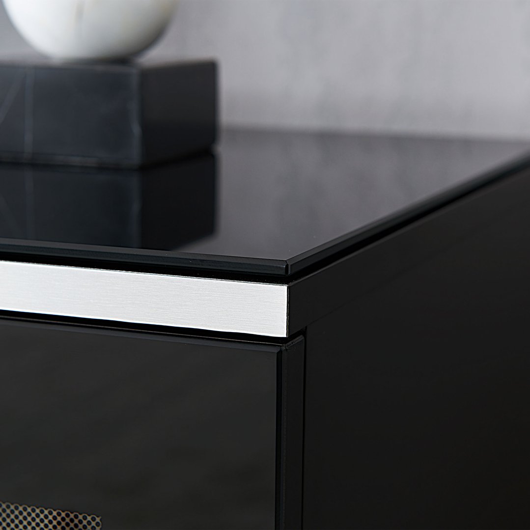 Close up of the corner of a black tv cabinet with a silver trim