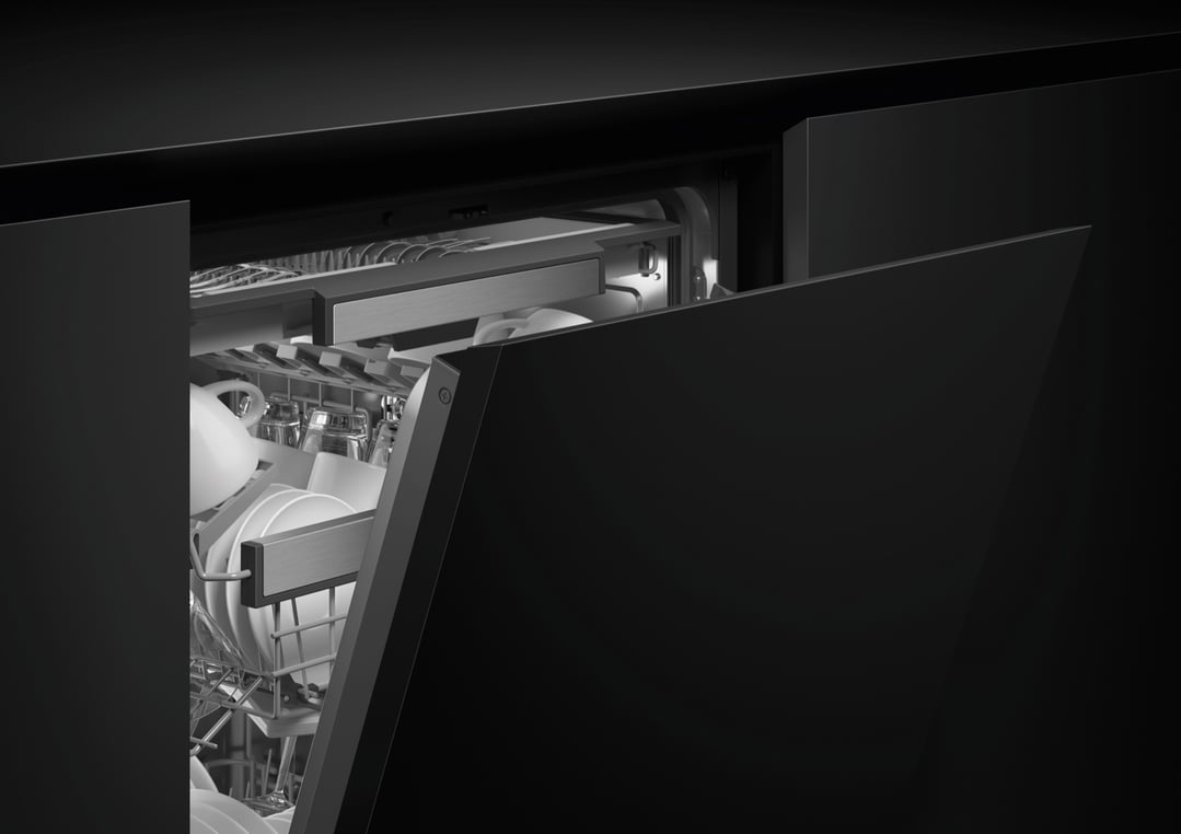 Integrated dishwasher with door ajar, showing dishes and glasses inside