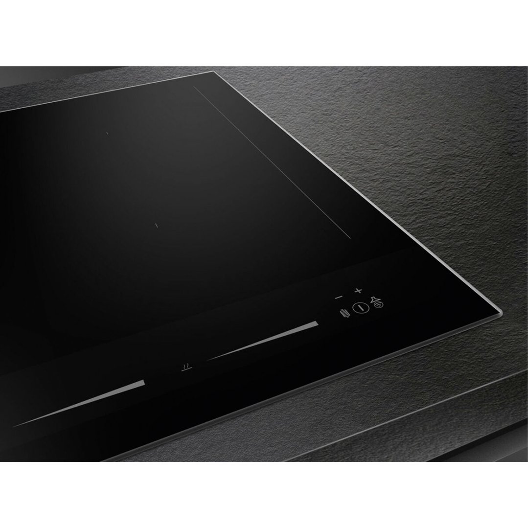 Close-up of a black induction cooktop with controls on a dark countertop