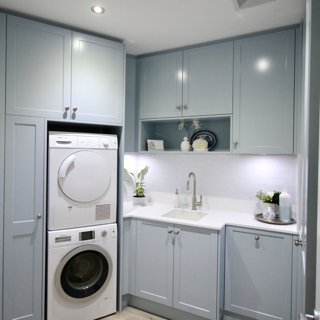 A white TINECO sink in a light blue laundry room with appliances