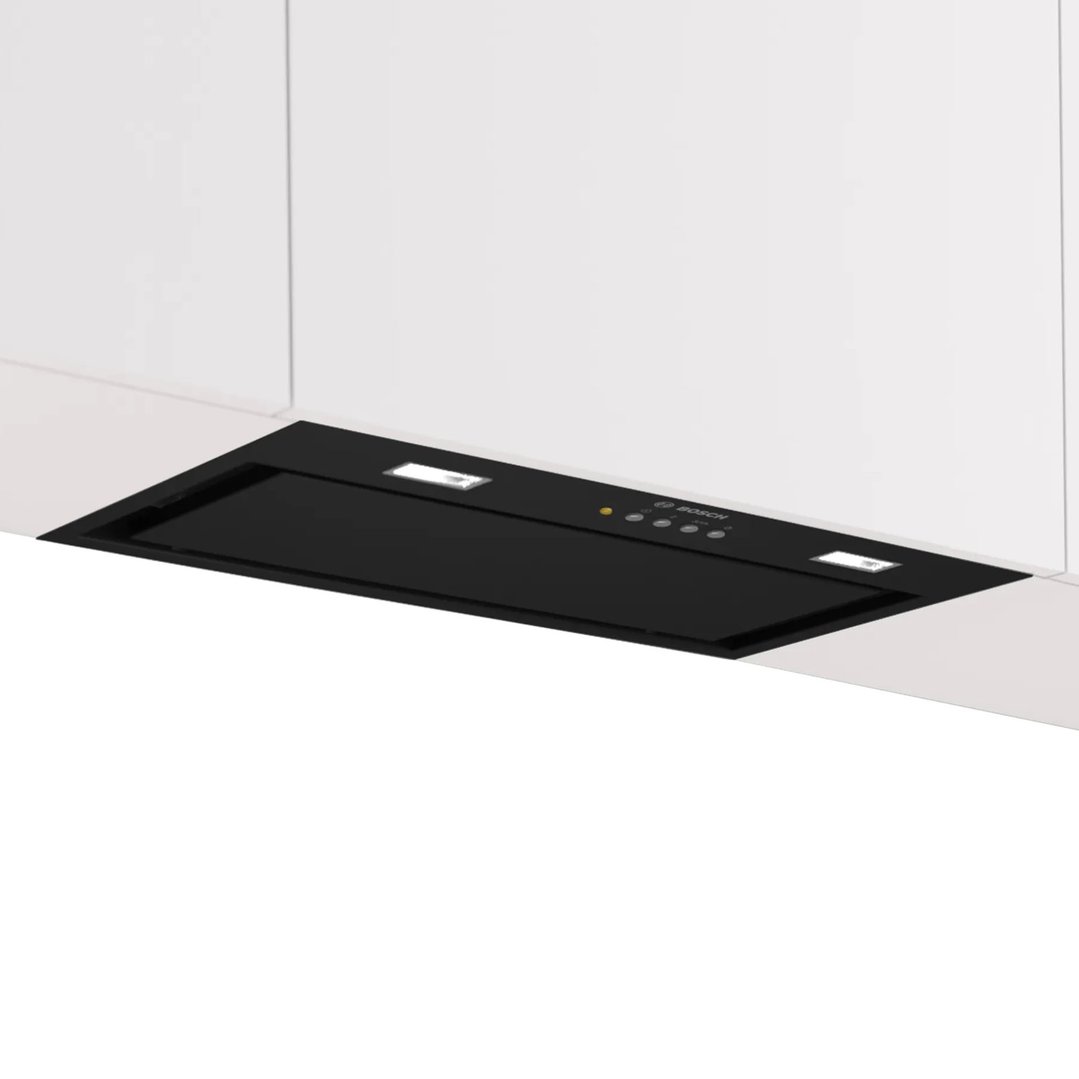 Black integrated rangehood with lights and controls installed under white kitchen cabinets