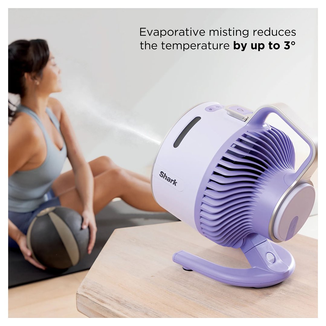 Woman exercising with a medicine ball while a Shark portable fan mists her