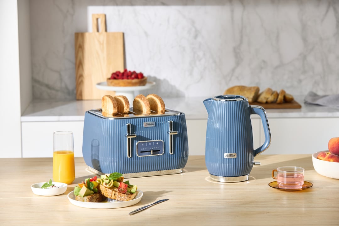 Blue toaster and kettle on a wooden counter with breakfast items