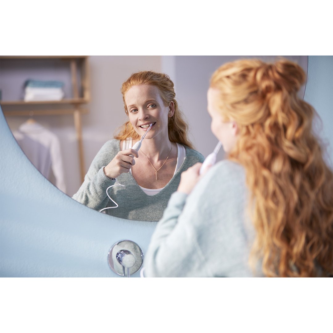 Woman using a Philips Sonicare Power Flosser in front of a mirror