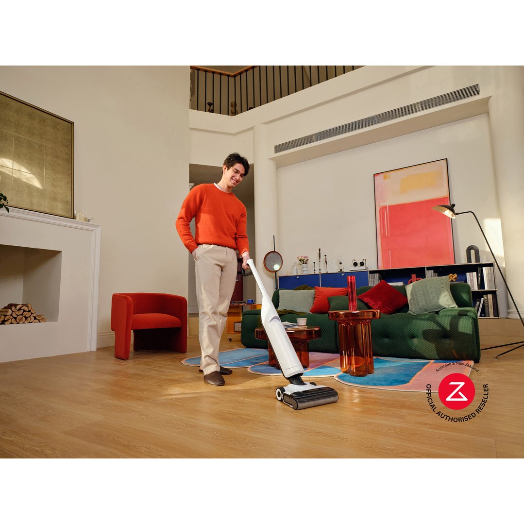 Man using a white vacuum cleaner on a wooden floor in a modern living room