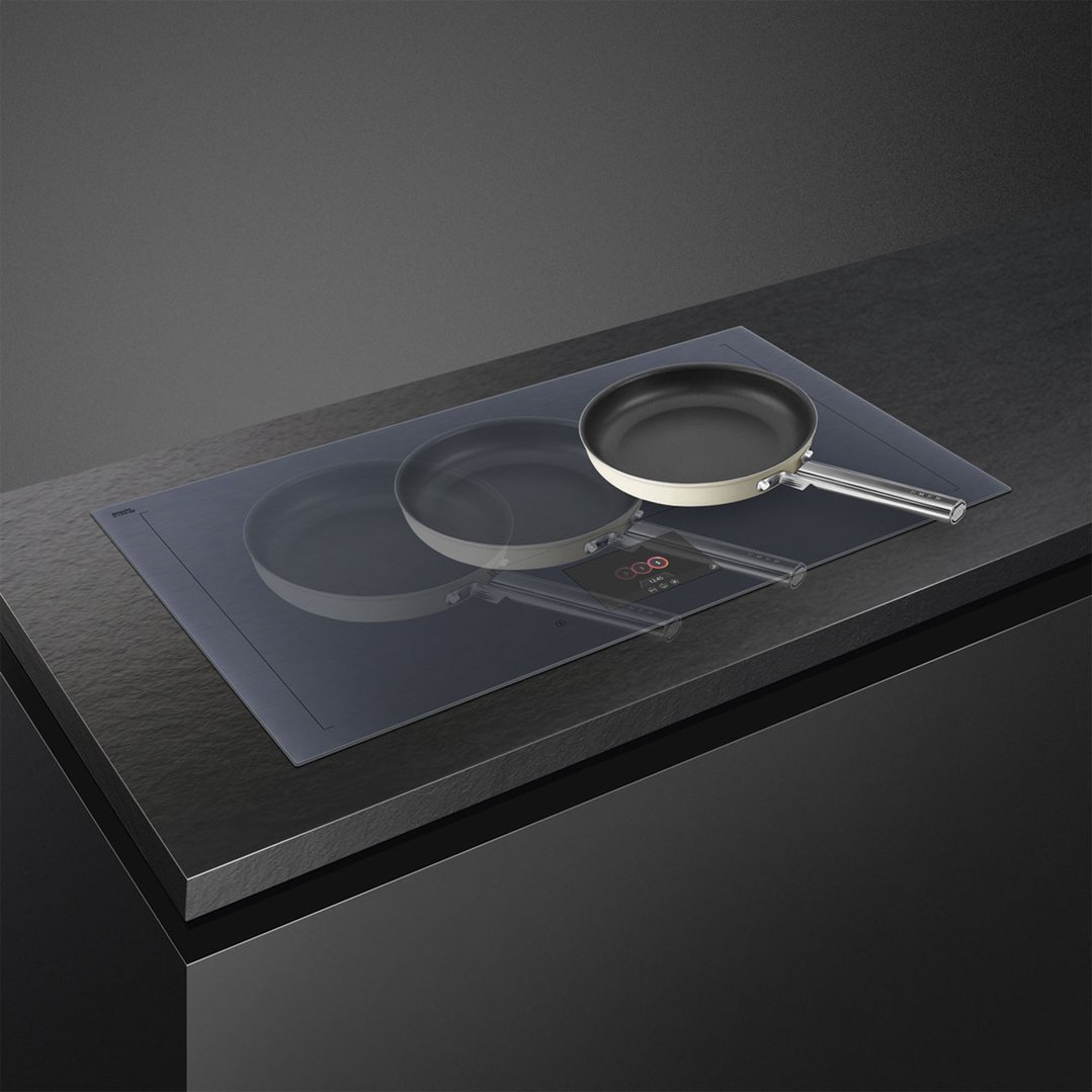 Induction cooktop with two pans on a dark countertop in a modern kitchen
