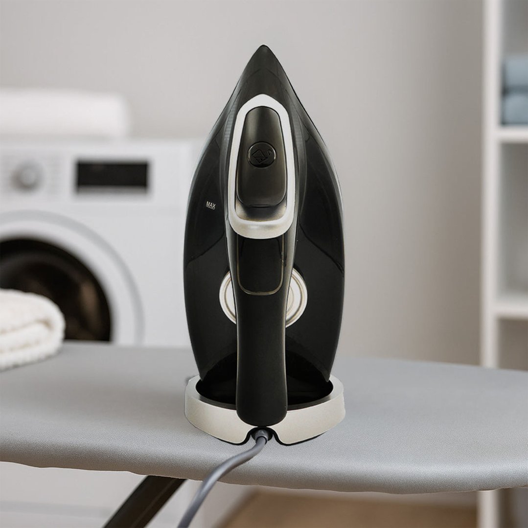 Black and silver steam iron on an ironing board in a laundry room