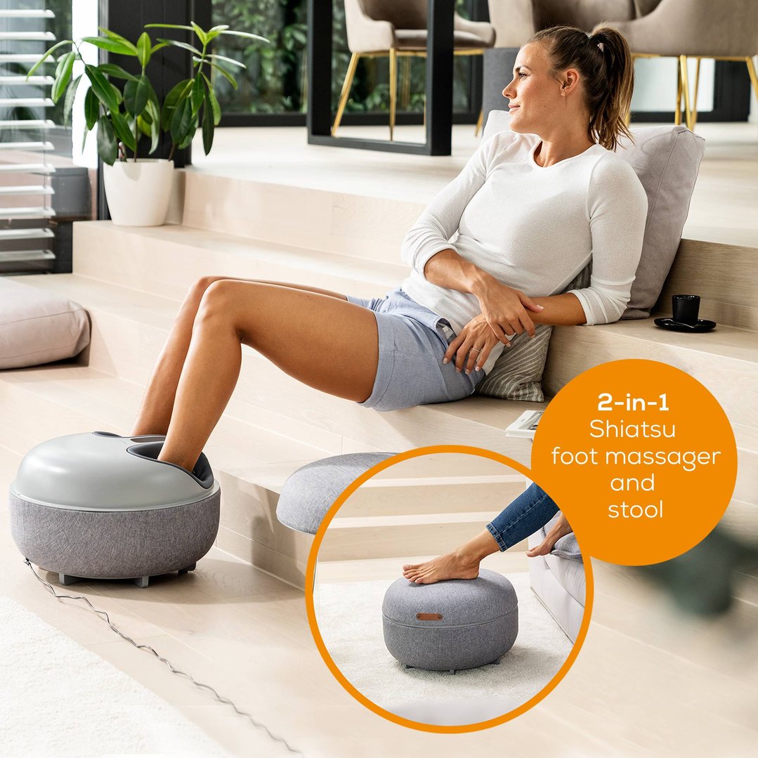 Woman using a 2-in-1 Shiatsu foot massager in a modern living room