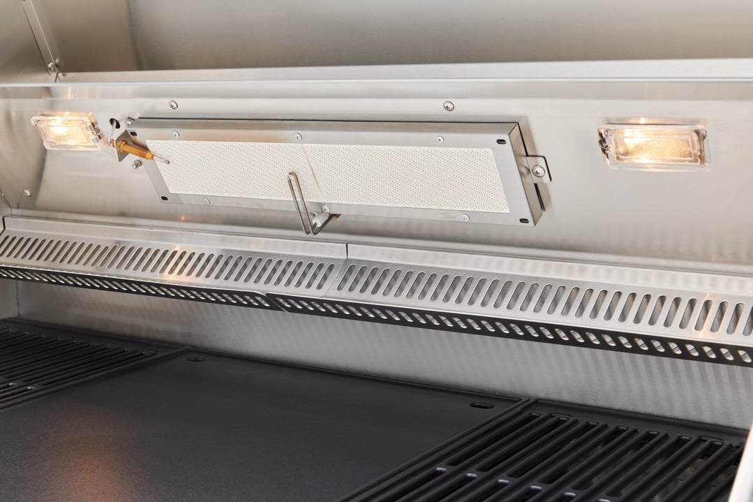Close up of the interior of a stainless steel barbecue with lights on