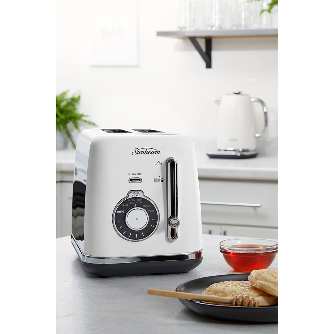 White Sunbeam toaster on a kitchen counter with breakfast items and kettle